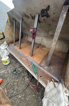 Loader bucket edge held in position with clamps and bracing before welding