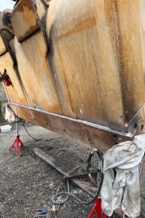 Bucket supported on jack stands with a new edge tacked in place