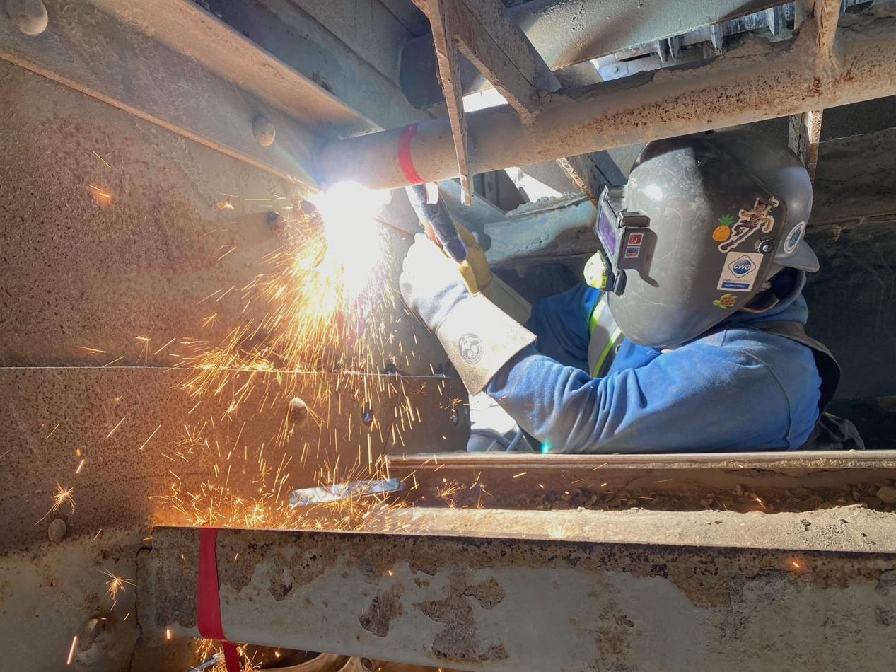 Certified welder working inside a steel structure with sparks falling