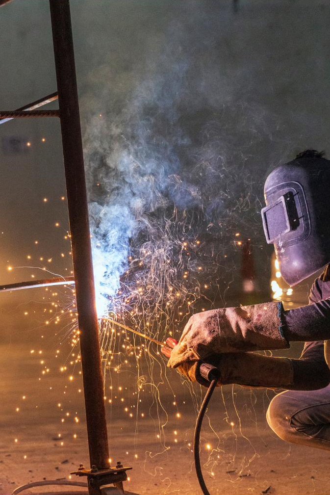 Welder working at the base of a steel column