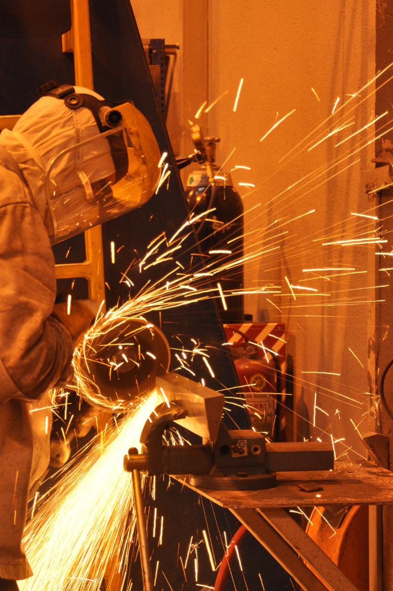 Torsten welder working inside a steel structure with sparks falling around them